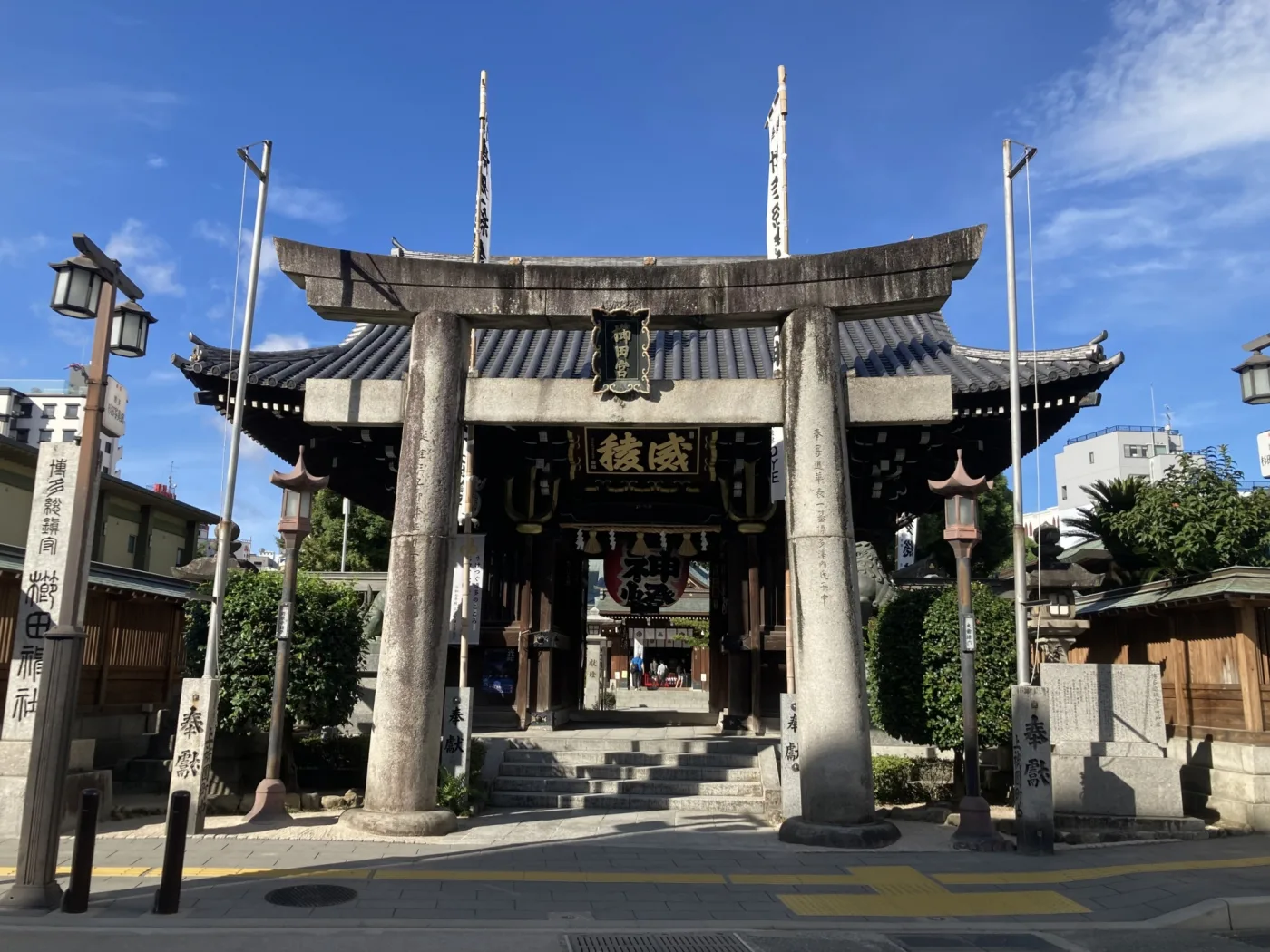 青空の下に立つ櫛田神社の石造りの鳥居と楼門